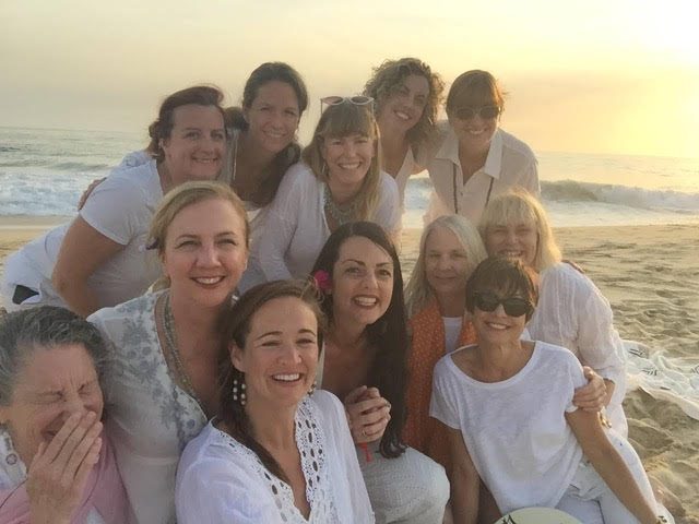 a group of women posing for a photo on a beach