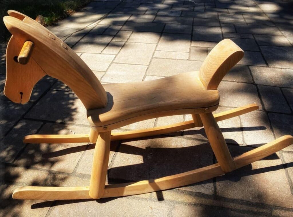 a wooden rocking horse on a brick path